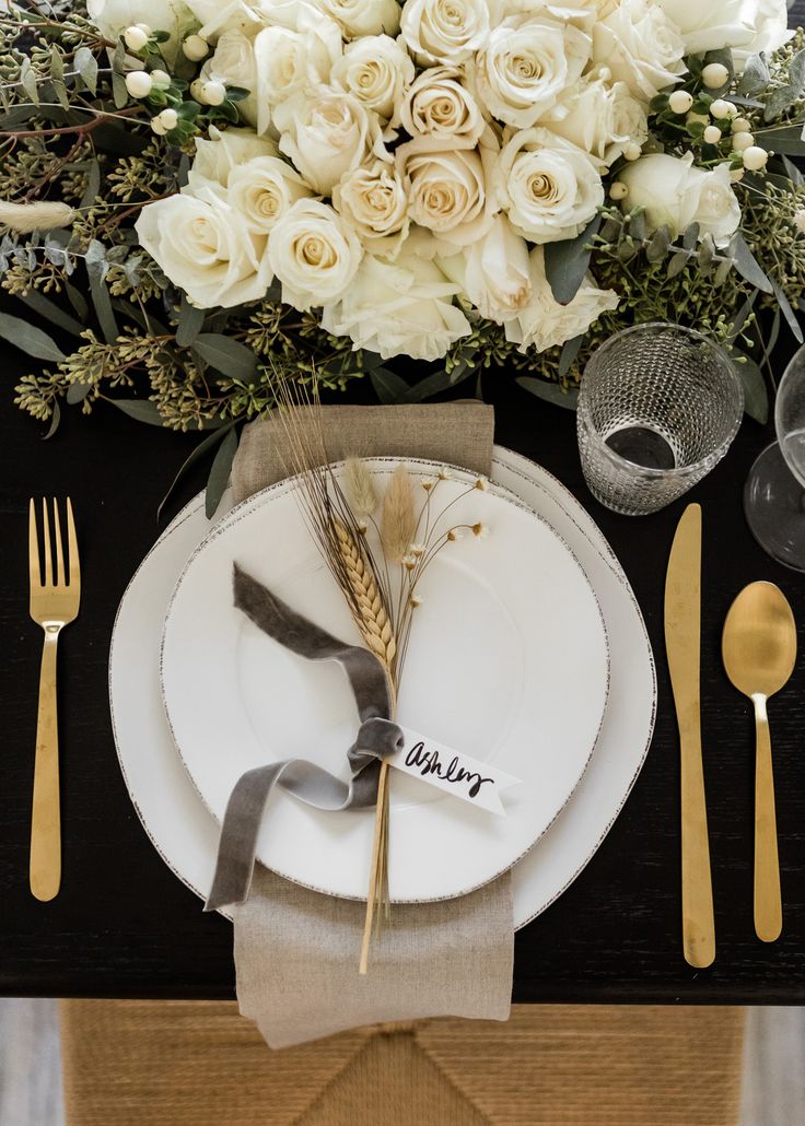 a table setting with white roses and silverware