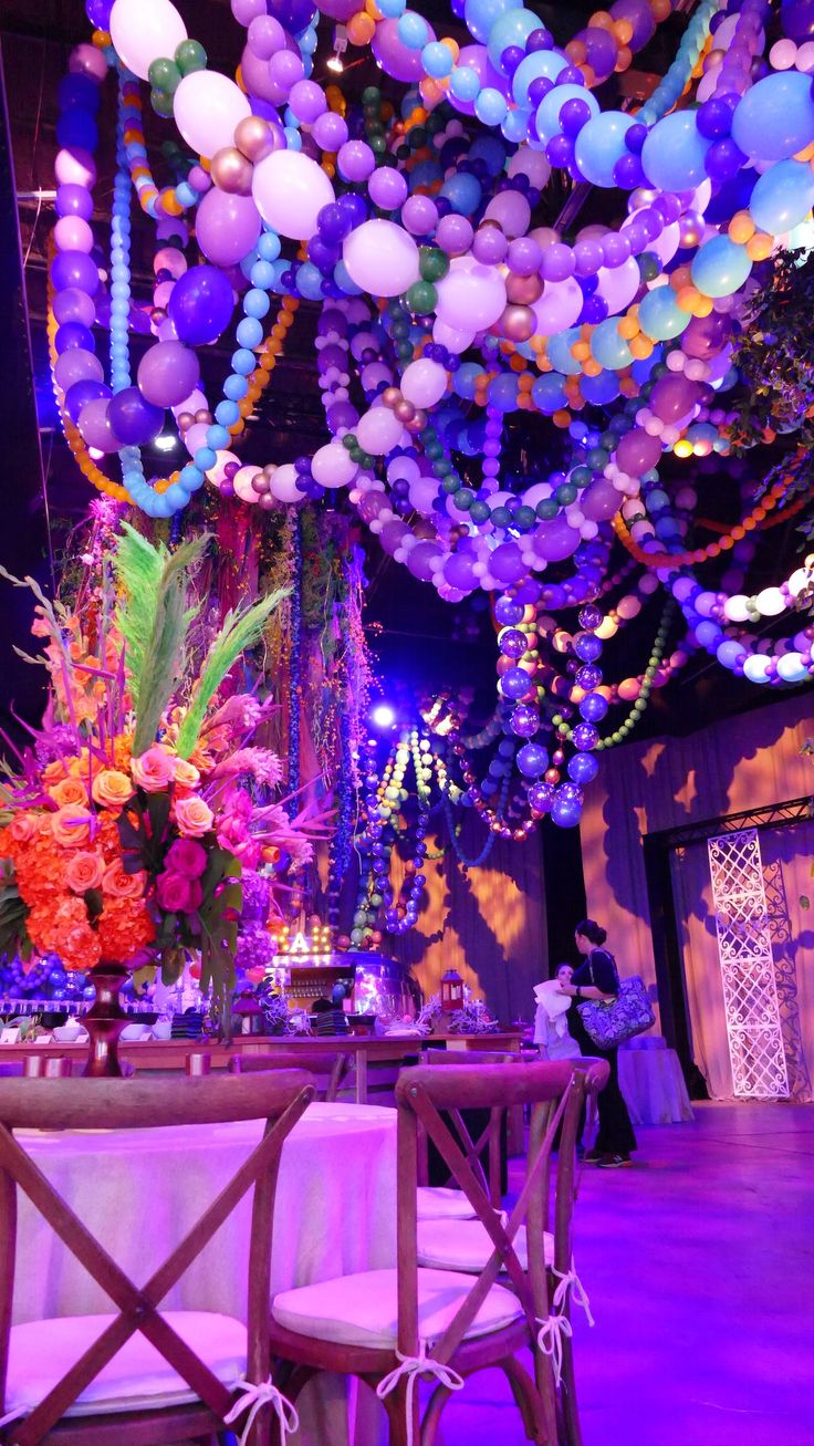 an image of a party setting with balloons on the ceiling and tables set up for dinner