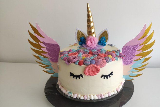 there is a cake decorated with an unicorn's face and wings