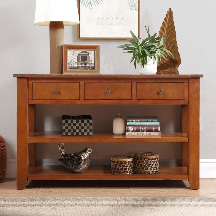 a wooden shelf with baskets on top of it next to a lamp and potted plant