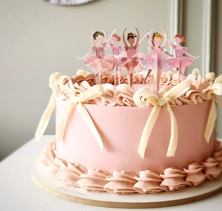 a pink cake with little figurines on top