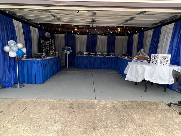 a party tent set up with blue and white draping, balloons and decorations