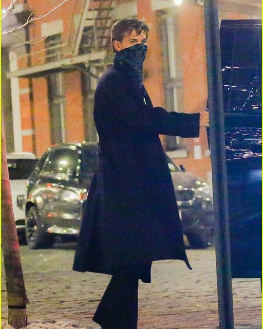 the man is walking down the street with his face covered by a black mask on