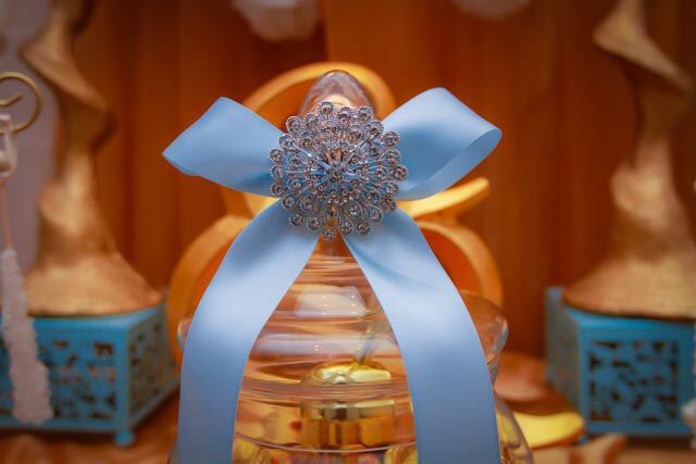 a glass vase with a blue bow on it's top and other decorative items in the background