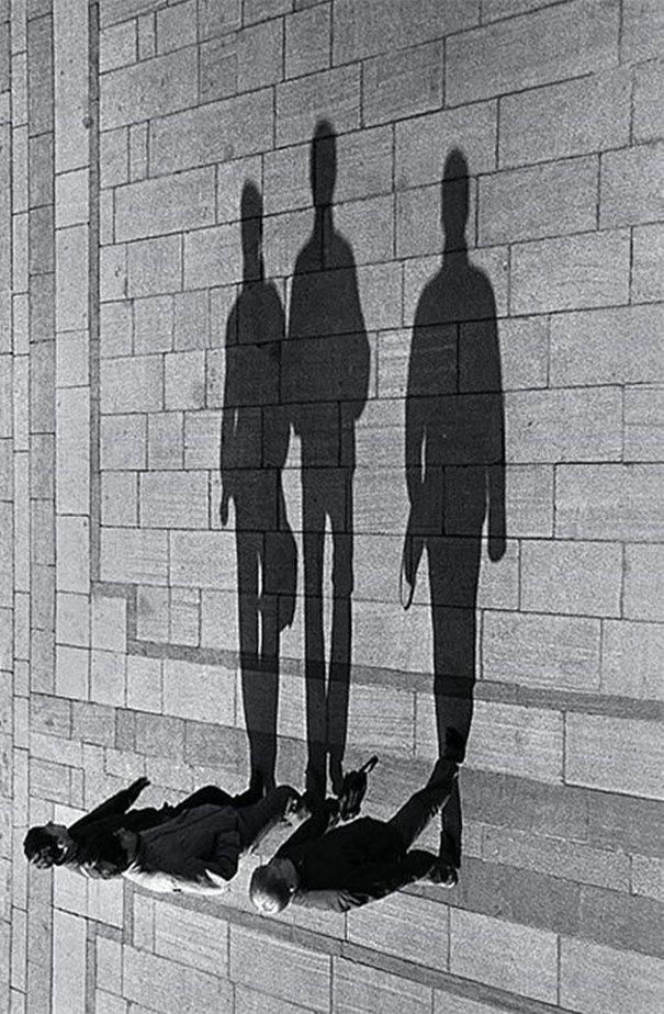 the shadow of two people standing next to each other on a wall with dead animals