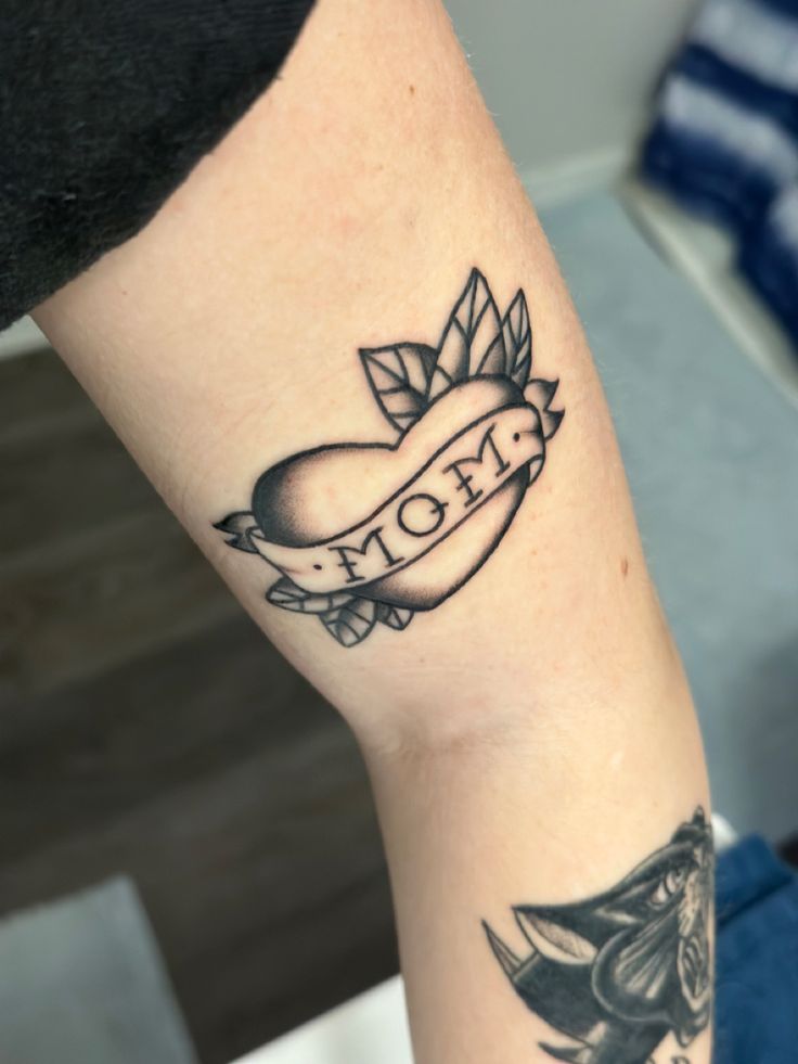 a woman's arm with a tattoo on it that says mom and an apple