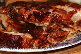 two pieces of meat sitting on top of a blue and white plate covered in sauce