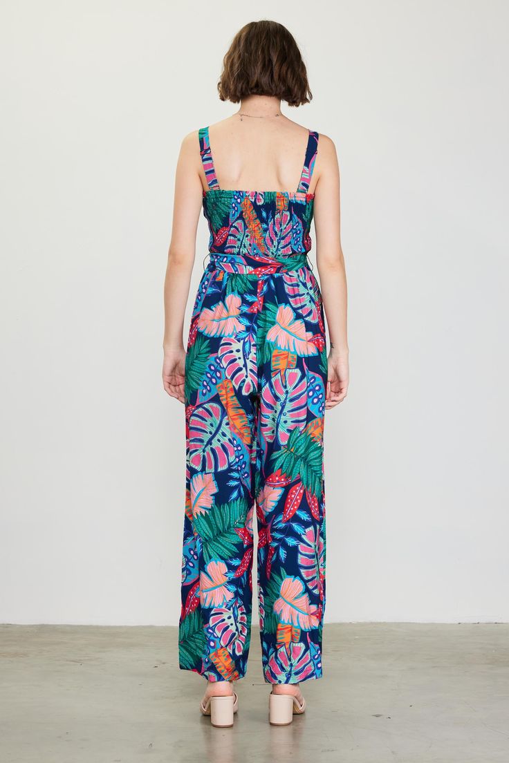 Fun, colorful, and impossible to ignore in a tropical floral print, this strappy jumpsuit is the ideal way to spice up your warm-weather wardrobe. It's got a smocked bodice that's balanced by a wide, roomy cut through the legs. A self-tie belt completes the look. "•Gathered shoulder straps •Smocked bodice •Ruffle trim at neckline •Optional self-tie belt •Wide-leg silhouette Item Number: 74403 SELF: 80% RAYON 20% NYLONE LINING: 100% RAYON Bohemian Jumpsuits And Rompers With Smocked Bodice, Bohemian Sleeveless Jumpsuits And Rompers With Smocked Bodice, Bohemian Sleeveless Jumpsuit With Smocked Bodice, Summer Beach Jumpsuits And Rompers With Elastic Waistband, Bohemian Style Smocked Bodice Summer Jumpsuits And Rompers, Bohemian Jumpsuits And Rompers With Smocked Bodice For Summer, Casual Jumpsuits And Rompers With Smocked Back For Vacation, Summer Vacation Strapless Jumpsuit With Smocked Back, Spring Vacation Strapless Jumpsuit With Smocked Bodice