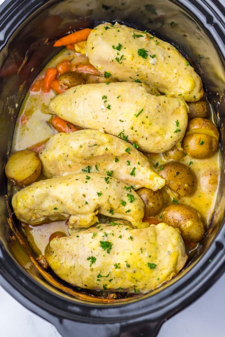 chicken, potatoes and carrots are in the crockpot with parsley on top