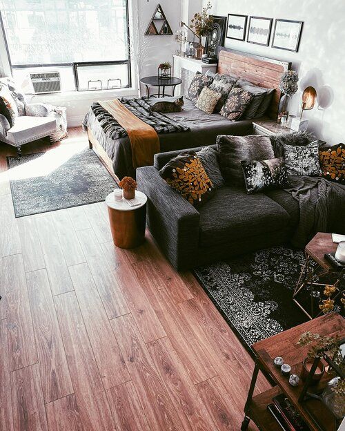 a living room filled with lots of furniture next to a large window on top of a hard wood floor