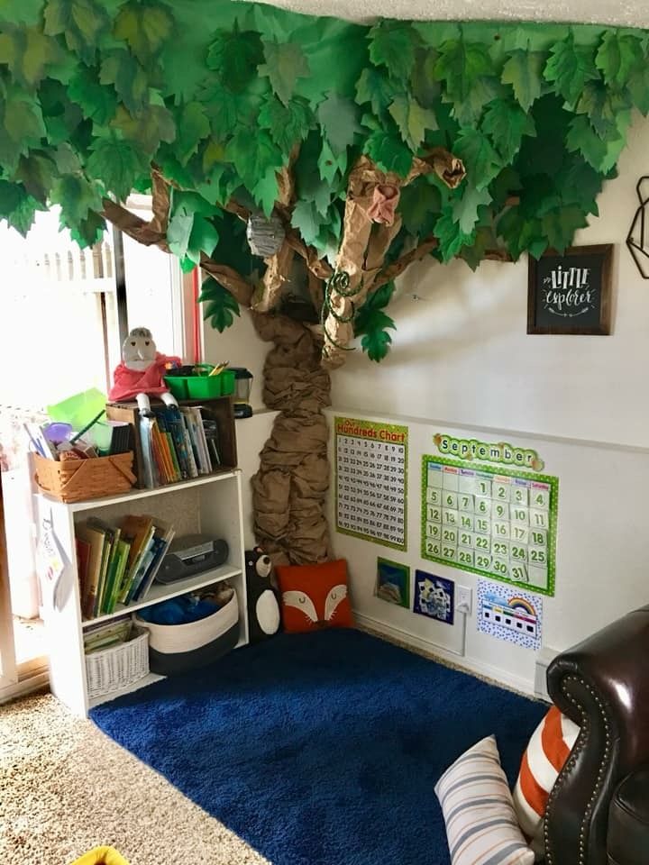 a living room with a tree, bookshelf and stuffed animals on the wall