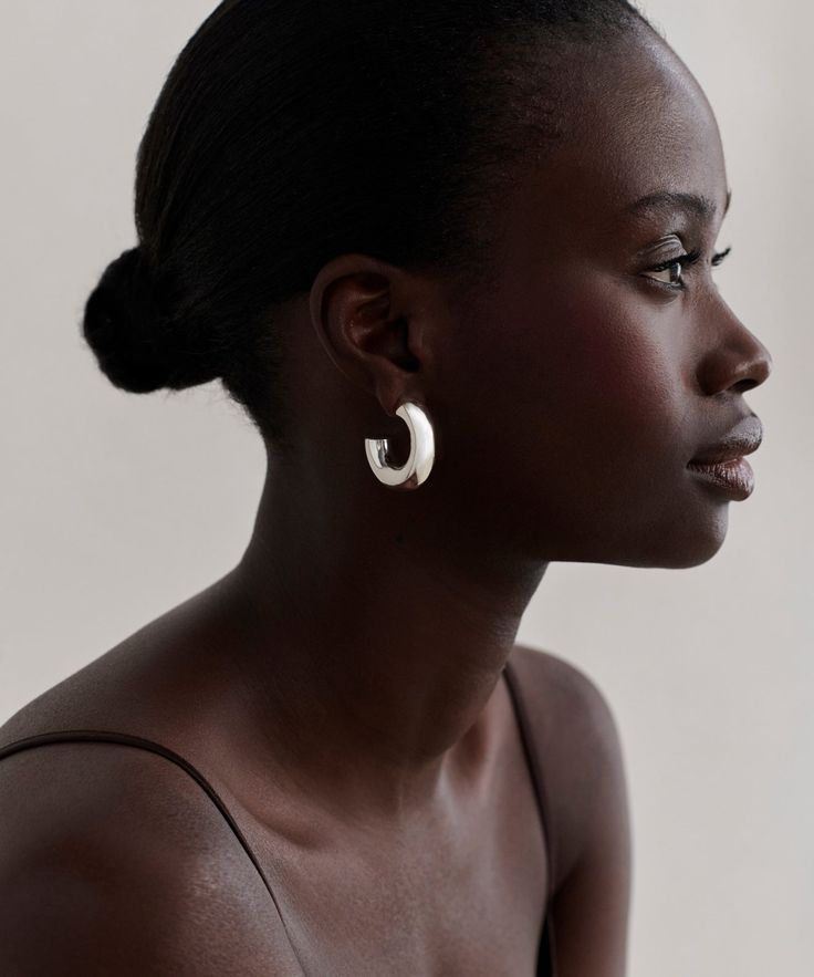 a woman wearing large white hoop earrings on her ear and looking off to the side