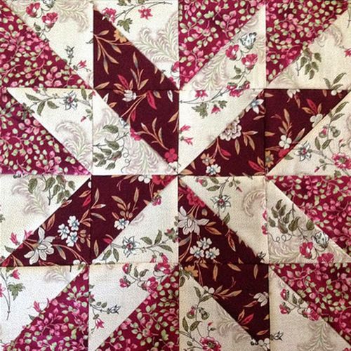 a red and white quilt with pink flowers on it's center piece, in the shape of a star