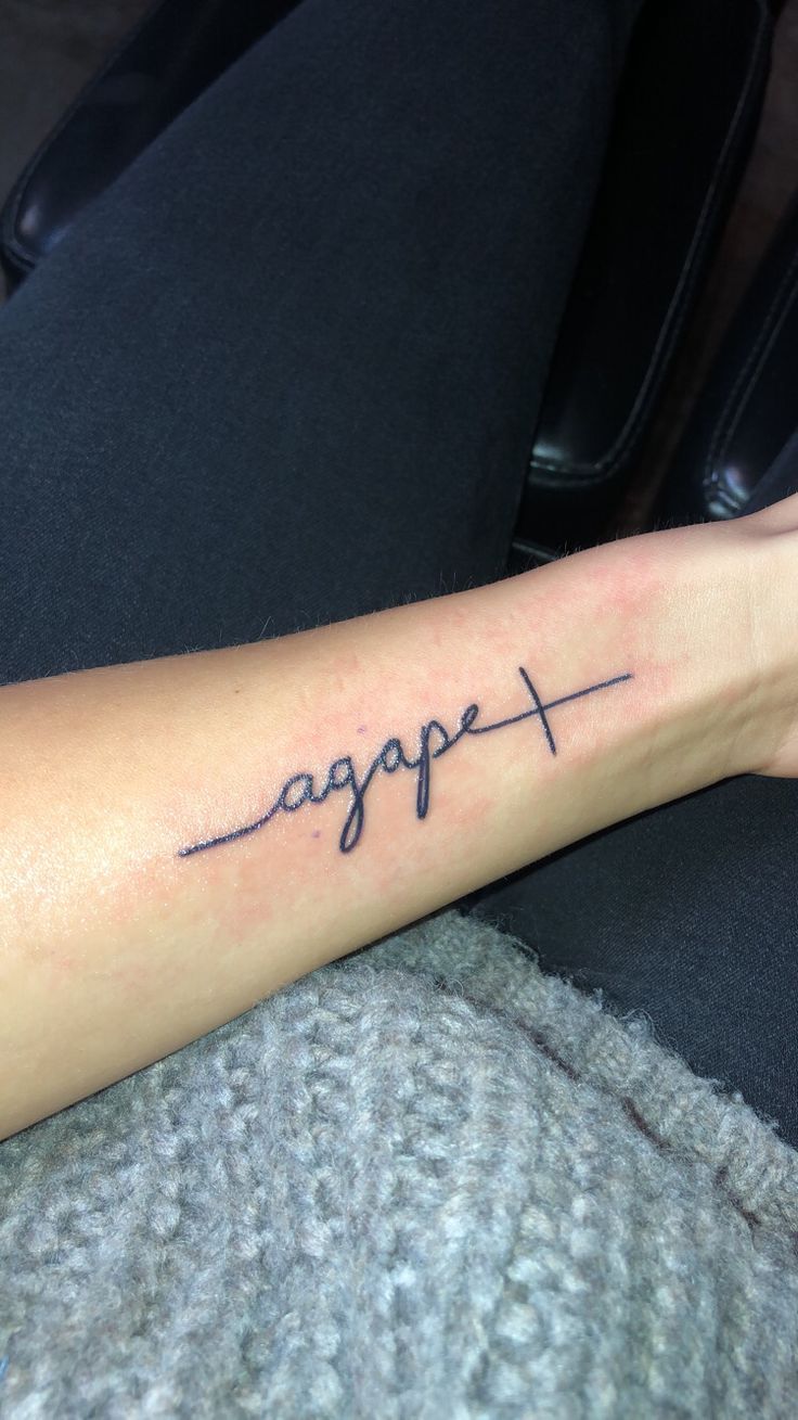 a woman's arm with the word hope written on it and a cross in cursive font