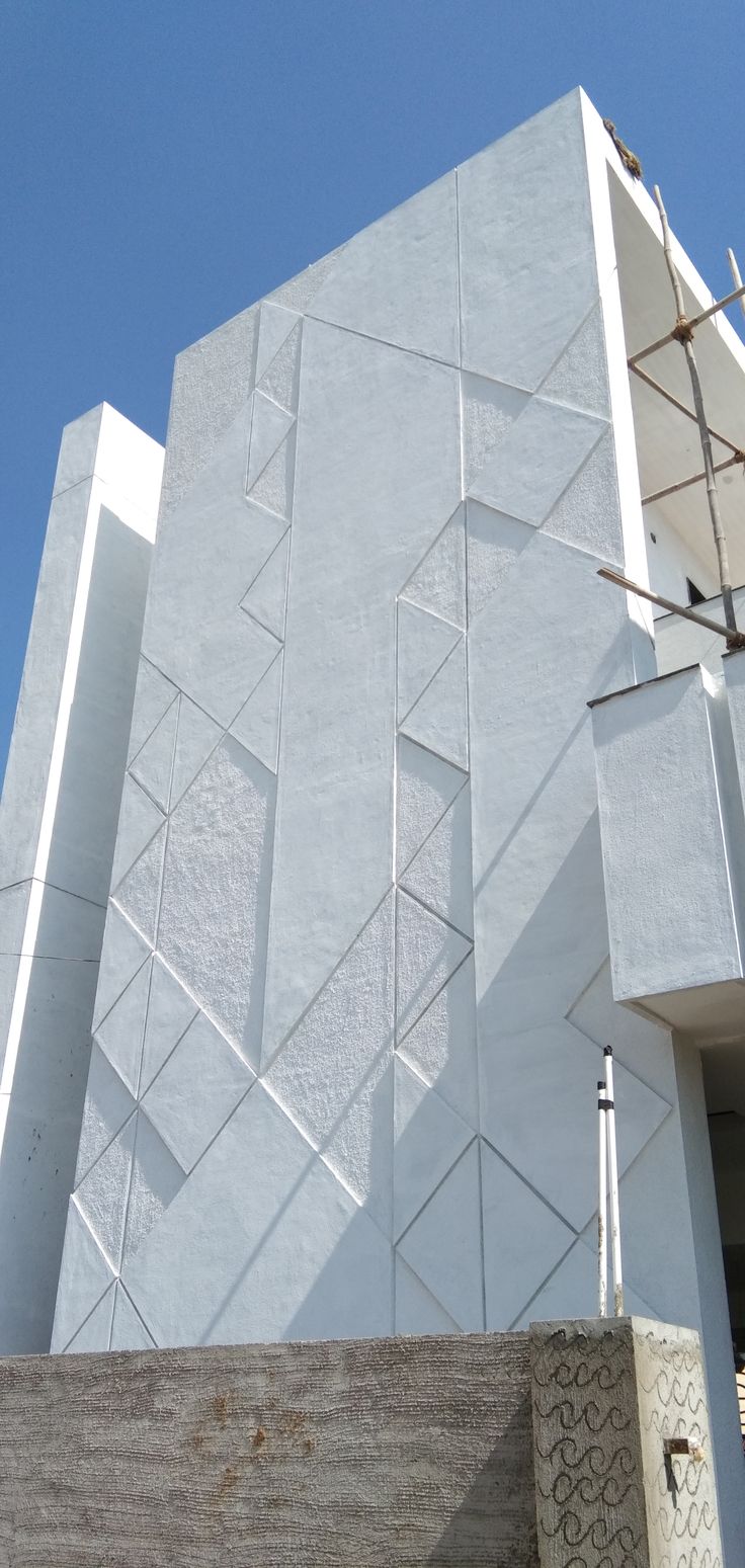 the side of a white building with scaffolding on it's sides and a blue sky in the background