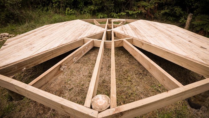 a wooden structure sitting on top of a grass covered field