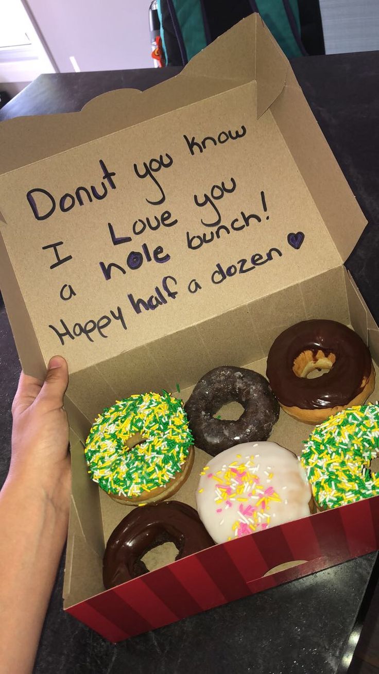 a box filled with donuts sitting on top of a table next to a sign