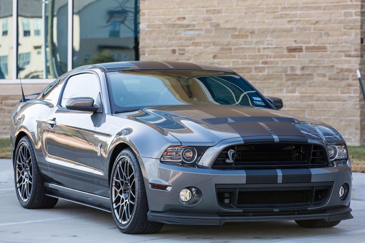 a silver mustang parked in front of a brick building