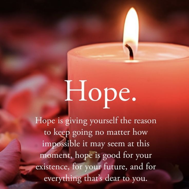 a candle with the words hope on it and pink flowers around it in front of a black background