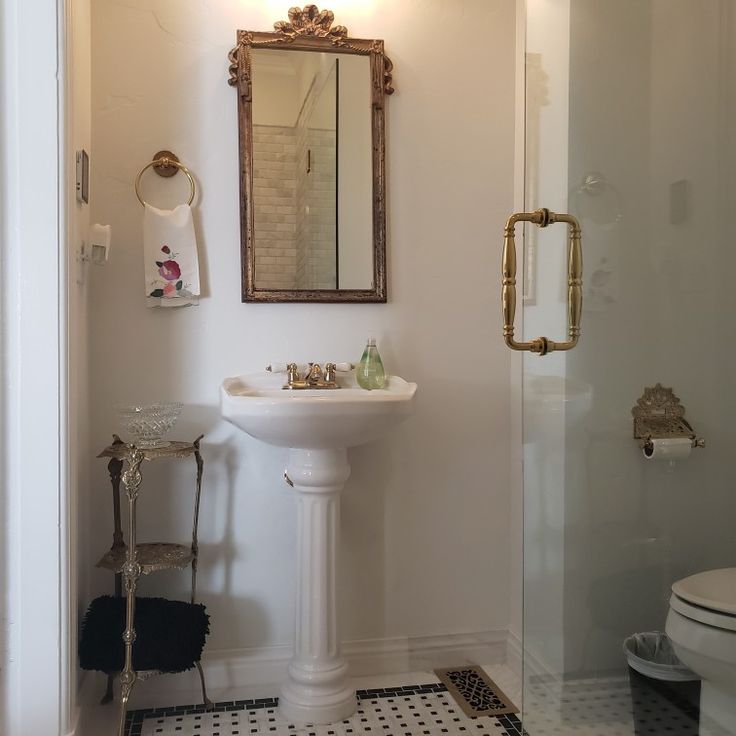 a bathroom with a pedestal sink, toilet and shower stall in the corner is shown