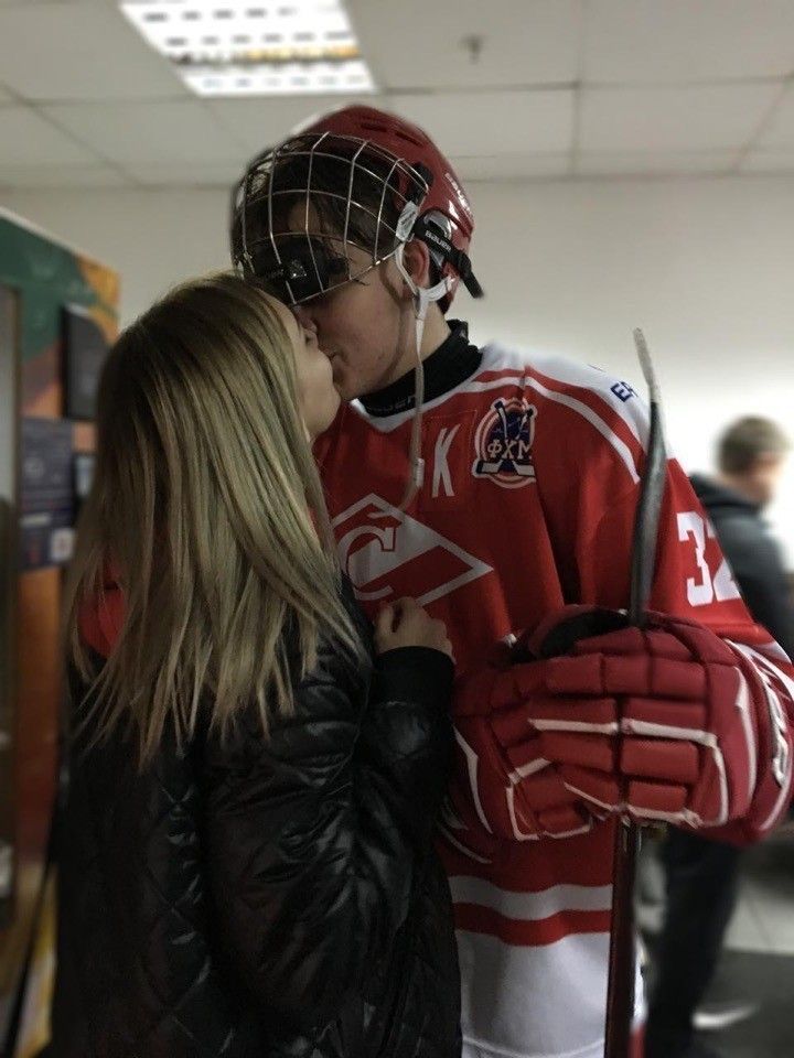 a man and woman kissing while wearing hockey gear