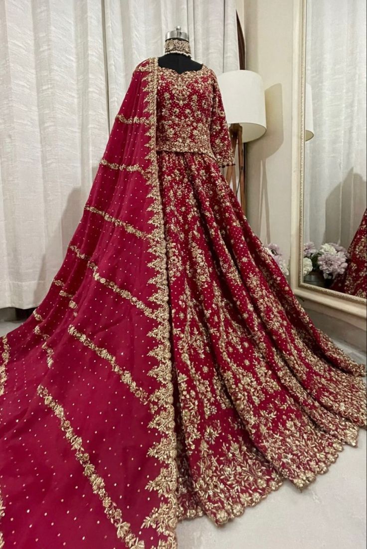 a red and gold bridal gown on display in front of a mirror