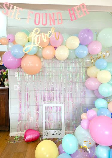 there are balloons and streamers on the floor in front of a party backdrop that says we found her love