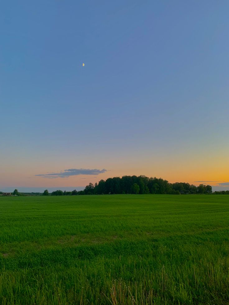 the sun is setting over an open field