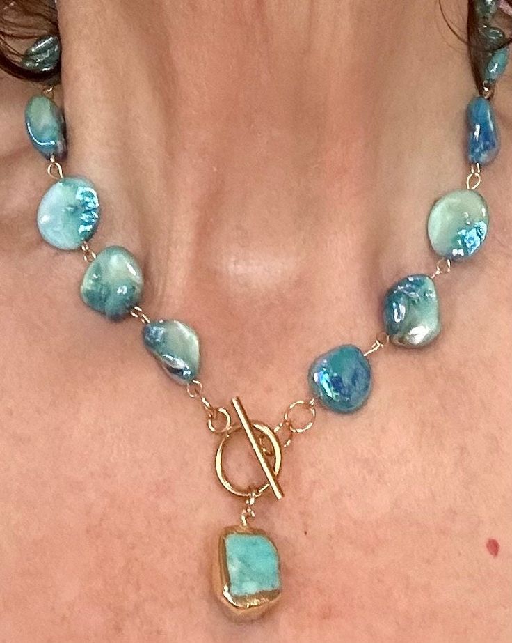 a close up of a woman wearing a necklace with blue beads and a musical note