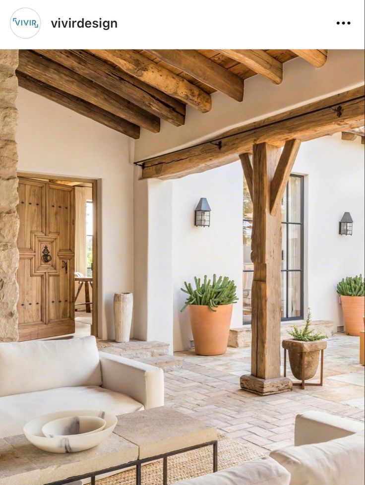 a living room filled with lots of white furniture and wooden beams on top of it