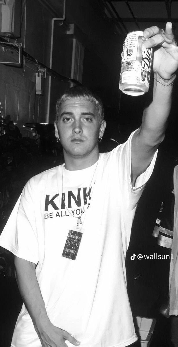 black and white photograph of a man holding up a can of drink in his hand