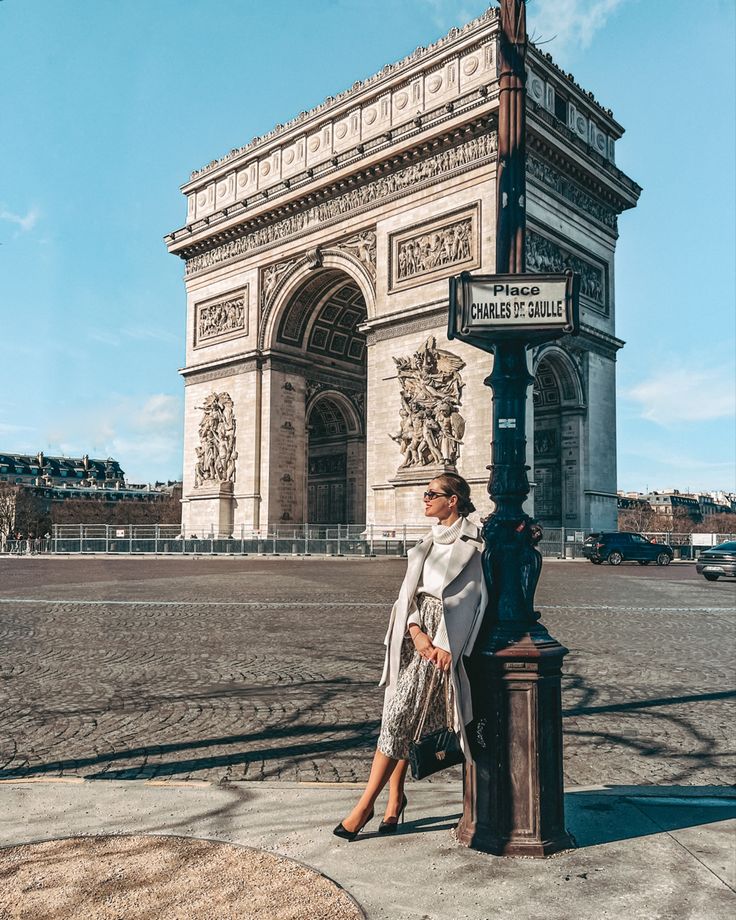 a woman standing in front of the arc de trioe