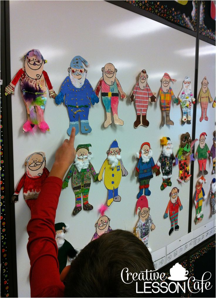 a child is pointing to a bulletin board with paper cutouts of people on it