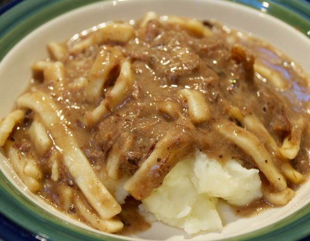 meat and gravy on top of mashed potatoes in a bowl