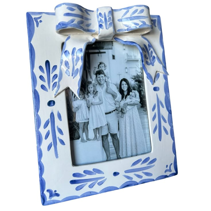 a blue and white photo frame with a bow around it's neck, decorated with flowers