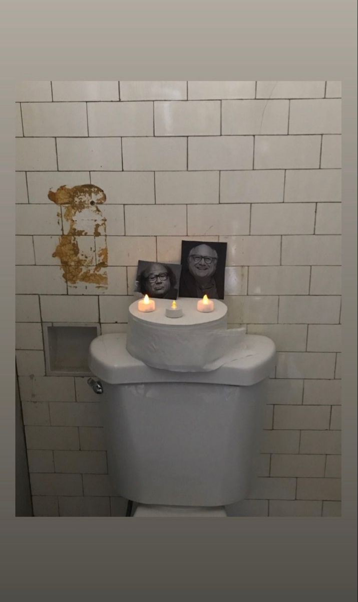 a white toilet sitting in a bathroom next to a wall with pictures on the tank