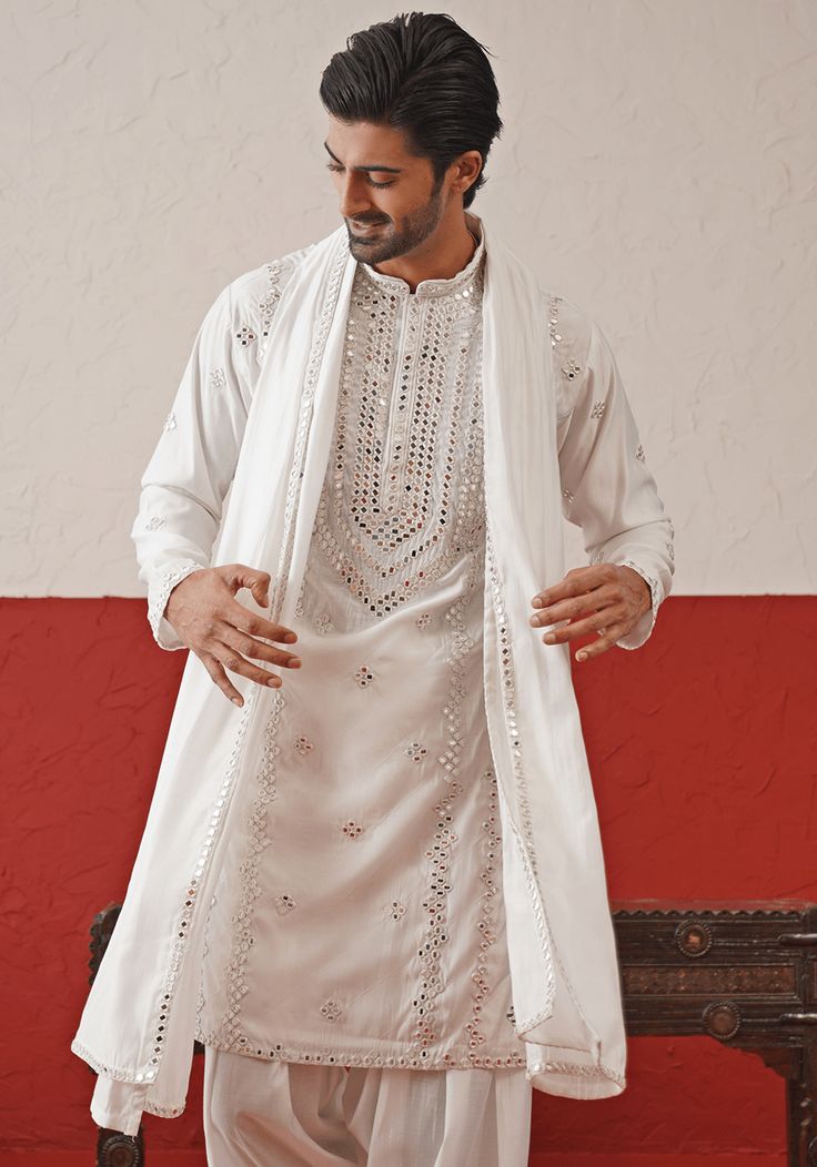 Elevate your style with White Embroidered mirror Kurta. Crafted from georgette, the classic white kurta features intricate hand embroidery and real mirror work, adding a touch of sophistication. Completed with a same-color embroidered dupatta and matching pants. Perfect for Sangeet, Mehendi, Haldi, or as a wedding guest outfit. Composition : Kurta, Patiyala & Dupatta : Viscose Georgette Care: Dry Clean Only and Vacuum Storage This product can be customized for sleeves, length and colour Delivery : 4-6 weeks as the product is hand crafted. Check Size Guide or choose MySize for free customisation (All Sizes above XL can be made at 15% additional cost) For more information and sizes please contact fabiliciousfashion@gmail.com or visit our Copenhagen studio. About the Designer : Welcome to Kal Elegant Traditional Wear With Mirror Work For Ceremonies, Designer White Kurta With Dabka Work, White Kurta With Dabka Work For Eid, Eid White Kurta With Dabka Work, Georgette Kurta For Traditional Ceremonies, White Semi-stitched Sherwani With Mirror Work, Transitional Georgette Kurta For Traditional Ceremonies, Traditional Ceremonies Georgette Kurta, White Sets With Mirror Work For Transitional Season