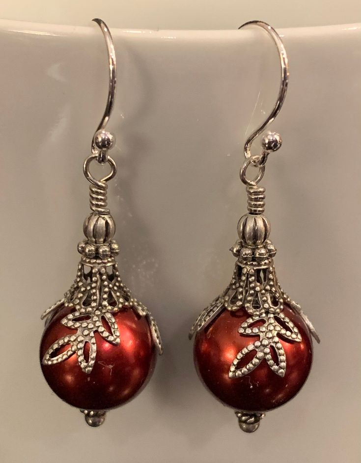 "Add a festive feel to your holiday wardrobe. Featuring 12mm Swarovski pearls with silver floral bead caps, filigree bell caps and antique silver findings that create the look of beautiful ornaments. Sterling silver ear wires and findings complete these fun to wear holiday earrings. Earring length: 1.5\" (including ear wire) All Moon Grove Designs jewelry comes beautifully gift boxed and ready for giving to yourself or someone special." Elegant Round Christmas Earrings, Elegant Christmas Celebration Earrings, Elegant Holiday Earrings For Festive Occasions, Elegant Festive Holiday Earrings, Elegant Holiday Festive Earrings, Elegant Silver Christmas Earrings, Elegant Silver Earrings For Christmas, Elegant Holiday Jewelry With Matching Earrings, Elegant Holiday Dangle Earrings