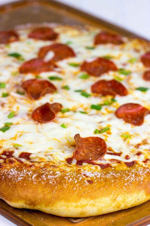 a pepperoni pizza sitting on top of a wooden pan covered in cheese and toppings