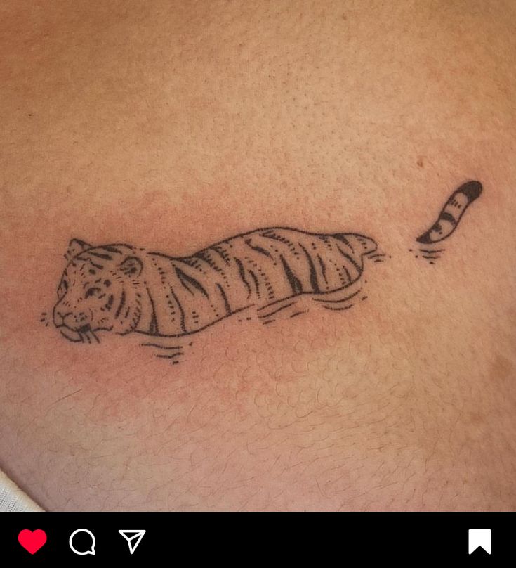 a small tiger tattoo on the back of a man's chest, with a feather flying through it