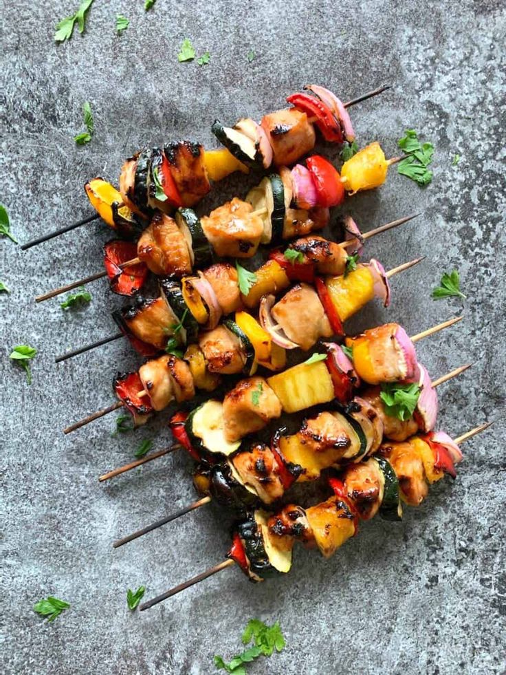 several skewers of meat and vegetables with limes on the side