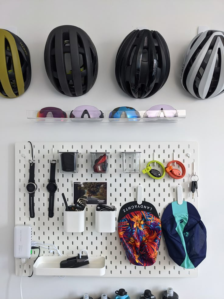 several different types of helmets are hanging on a pegboard with ear phones and other items