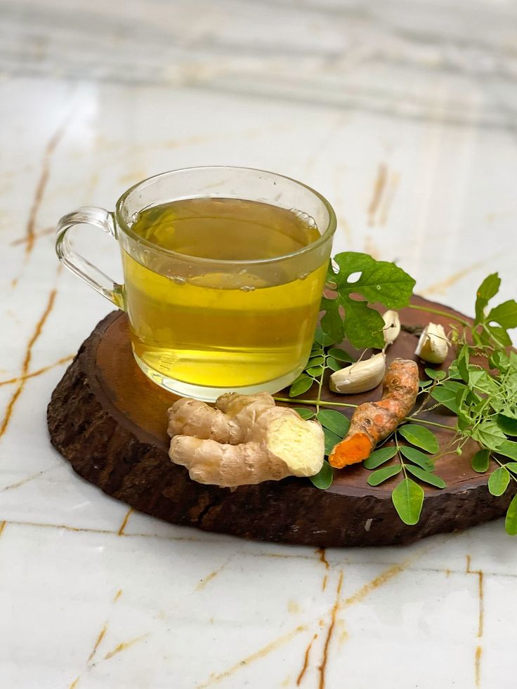 a cup of green tea and some vegetables on a wooden board with marbled surface