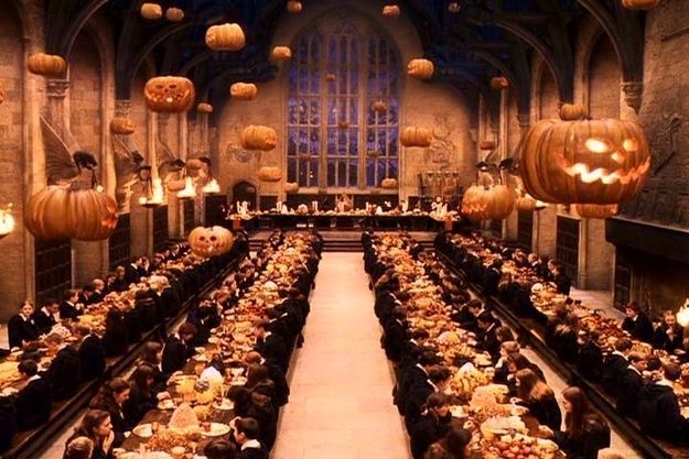 a large hall filled with lots of tables covered in halloween decorations and pumpkins hanging from the ceiling