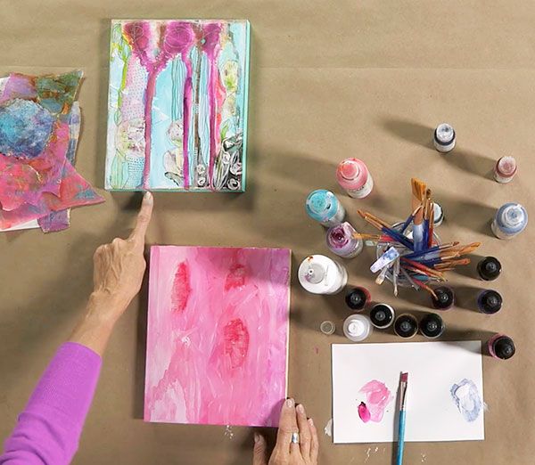 a woman is painting with her hands on the table next to some paint and paper