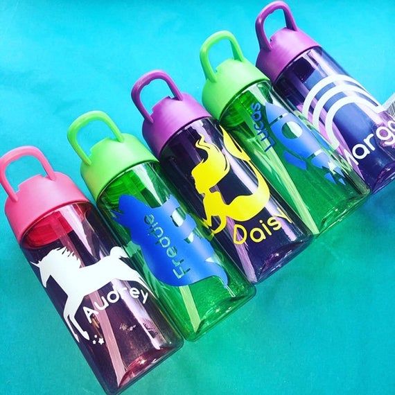 four colorful children's water bottles sitting next to each other on a blue surface