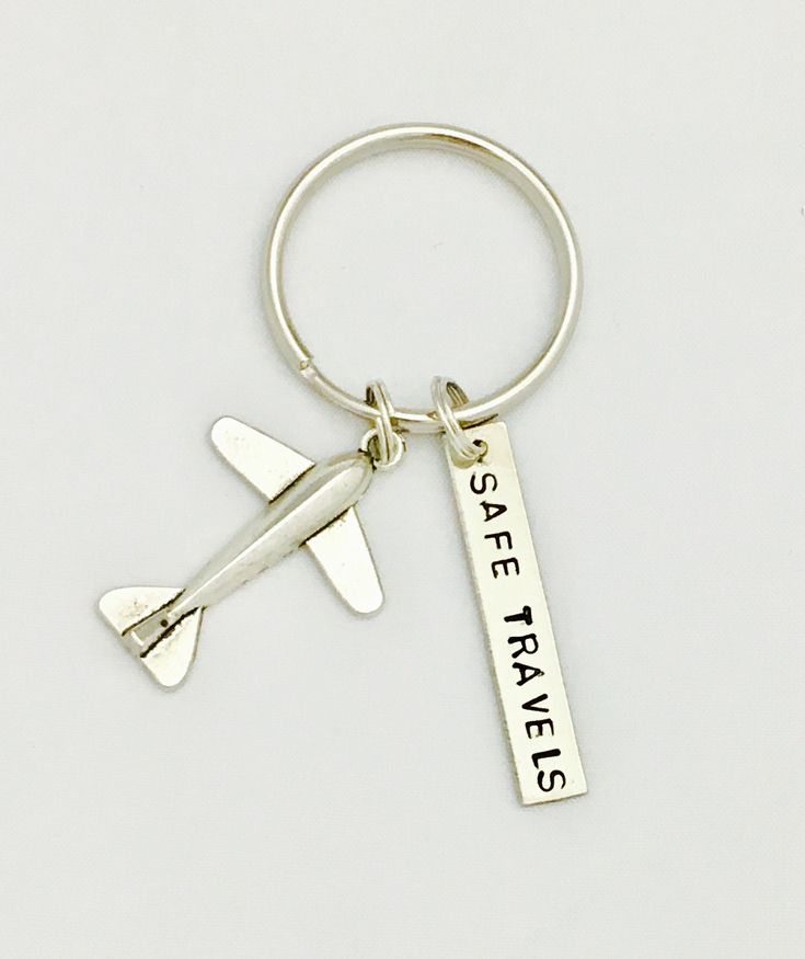 a silver keychain with a plane on it that says see travels and is hanging from the side