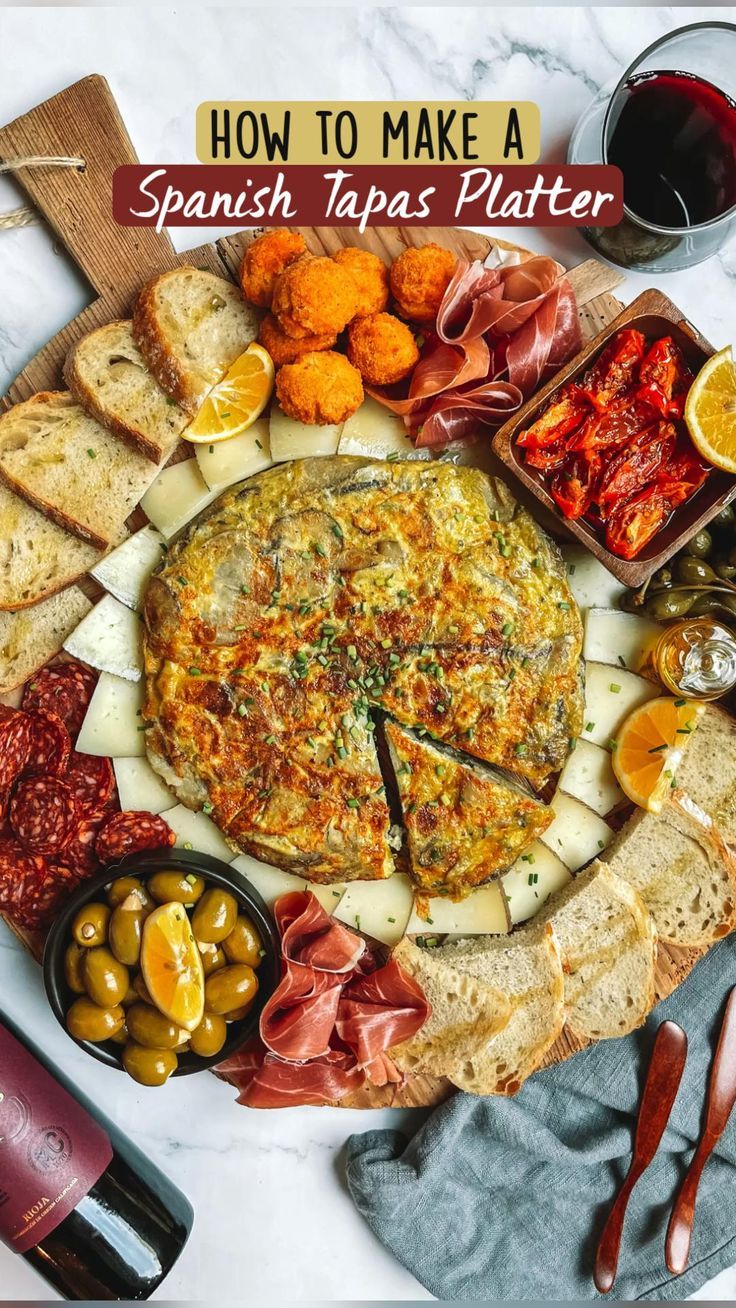 a platter with cheese, meats and bread on it next to wine glasses