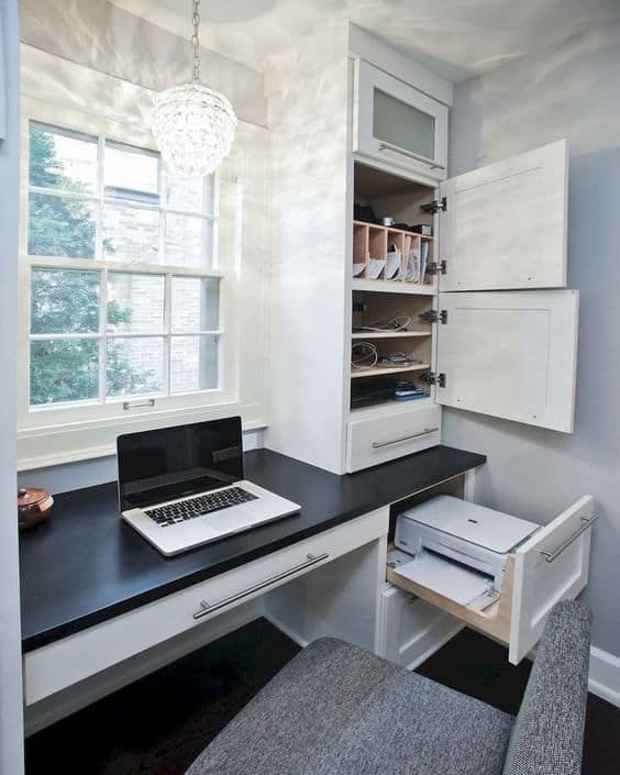 a laptop computer sitting on top of a desk next to a drawer filled with files