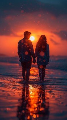 two people walking on the beach at sunset with their hands in each others'pockets